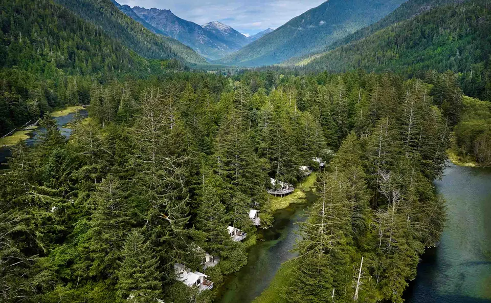 Clayoquot Wilderness Lodge safari tents beside the Bedwell River beneath forested Vancouver Island mountains